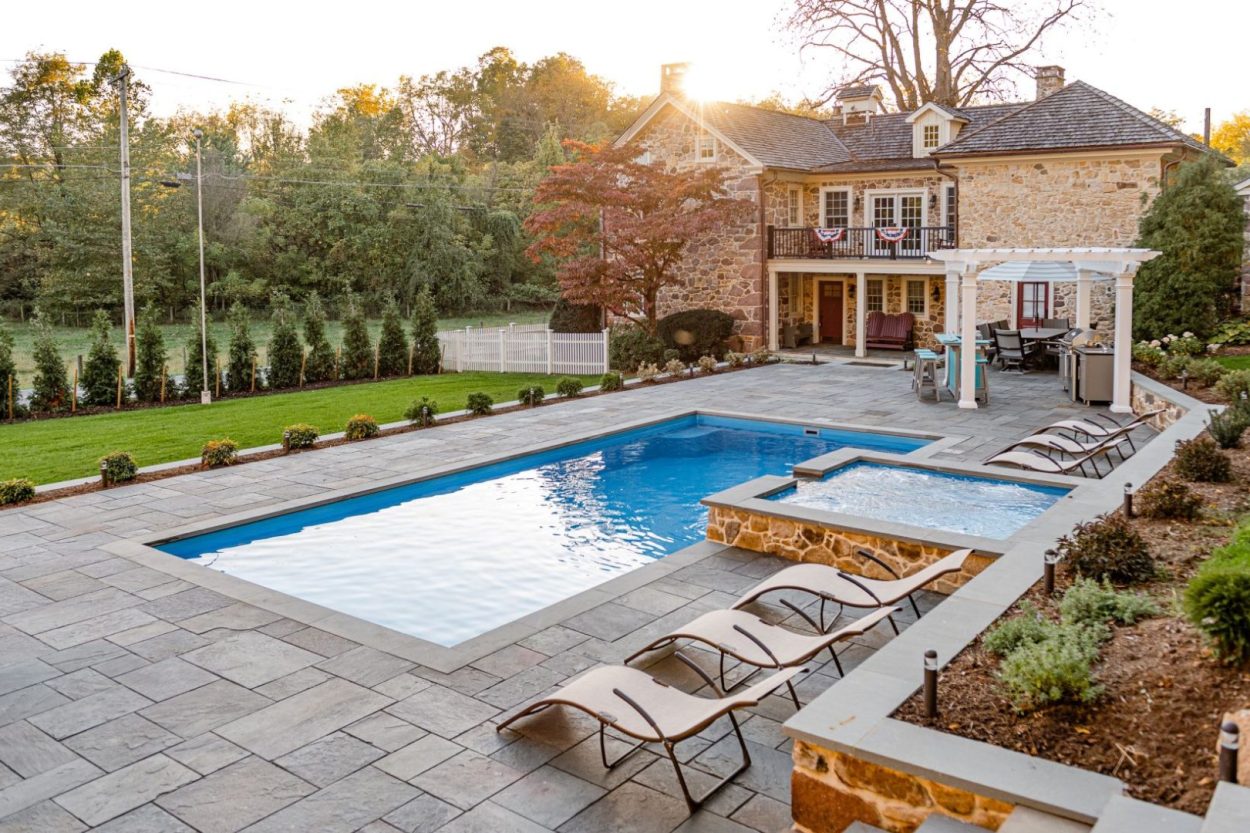 pool and spa surrounded by hardscape patio and pergola